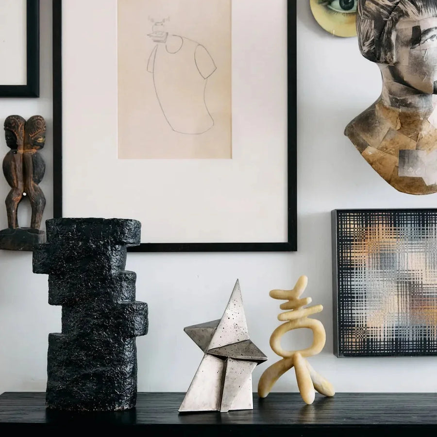 Schwarzes Sideboard mit drei Skulpturen vor Bilderwand mit Zeichnung und Kunstobjekten – moderne Wohnzimmer Deko